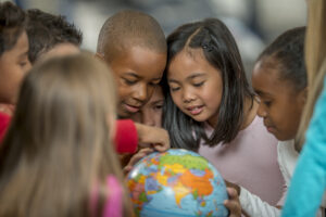 multi-ethnic group of elementary students looking at a globe