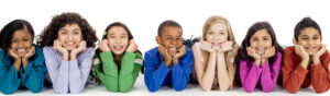 multi-ethnic group of elementary age children lying in a row smiling and looking at the camera